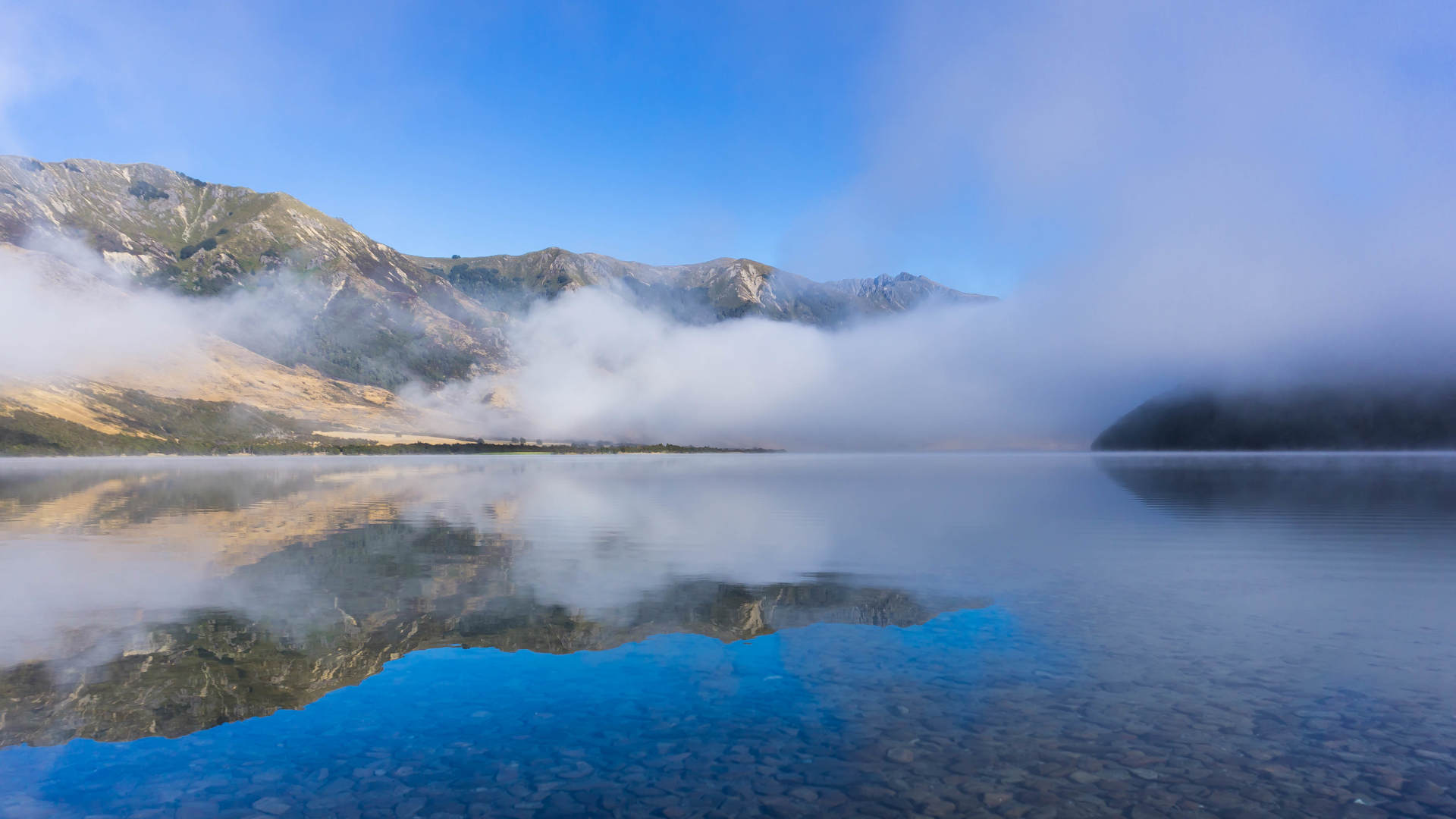 Clouds and hill reflecting in water of the lake in front of it (early morning shot)